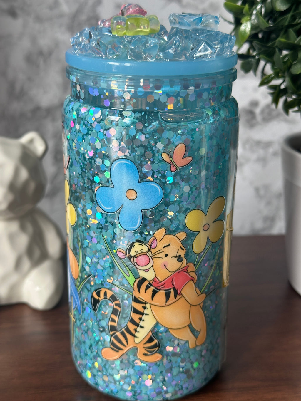 Image 2 (side - Tigger y Pooh): "Dreamy Blue Glitter Tumbler side view — Tigger and Pooh among flowers sublimation design on blue glitter tumbler, handcrafted at Motiva Ink Studio"

