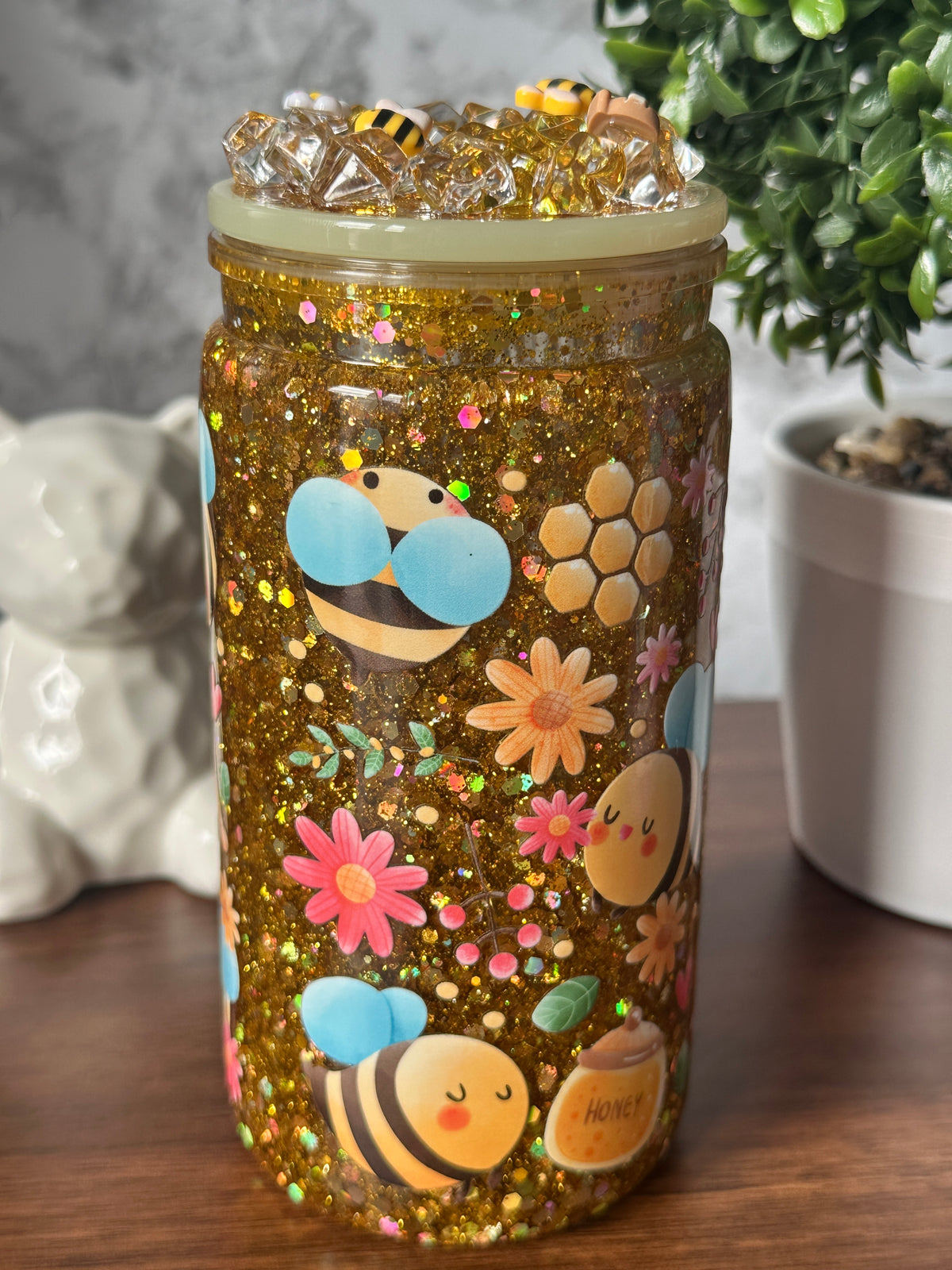 Image 1 (front): "Golden Glow Glitter Tumbler — 16 oz snowglobe tumbler with gold glitter finish, honeybee and flower sticker (uv dtf) design, handcrafted at Motiva Ink Studio"

