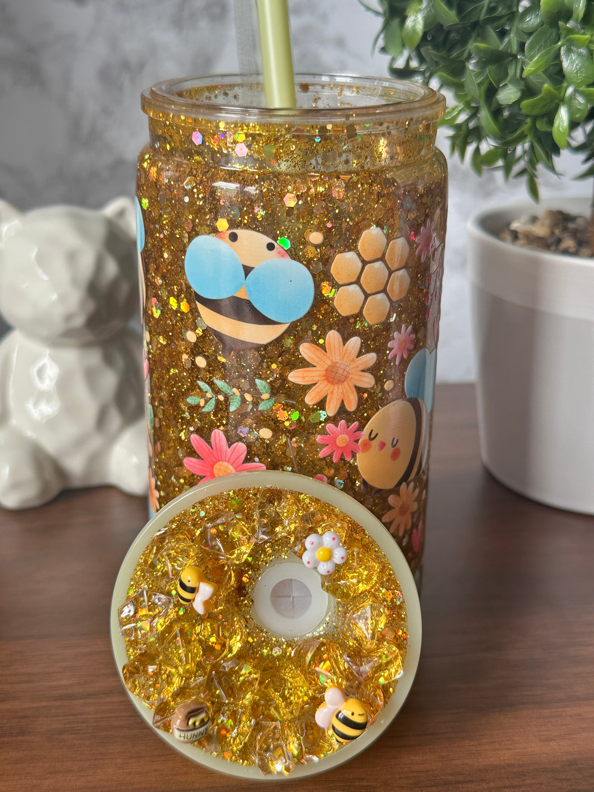 Imagen 2 (tapa): "Golden Glow Glitter Tumbler lid — decorated with honeybee and daisy charms, gold glitter accents, custom straw topper, handcrafted at Motiva Ink Studio"
