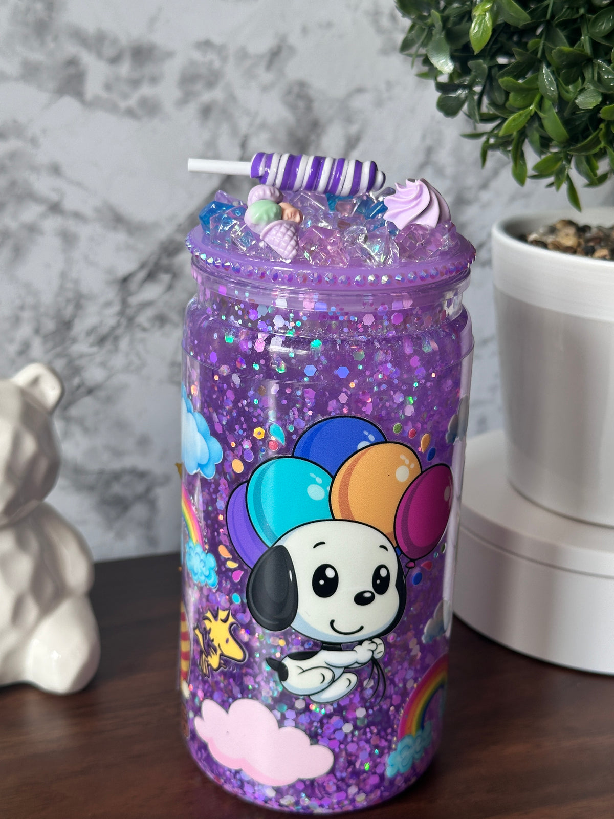 Imagen 1 (front): "Enchanted Lilac Glitter Tumbler — 16 oz snowglobe tumbler with lilac glitter finish and character with a balloons sticker (uv dtf) design, handcrafted at Motiva Ink Studio"

